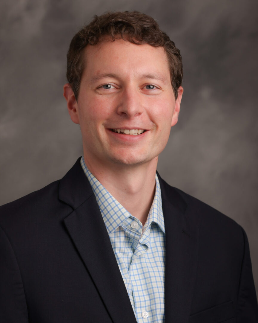 A man in a suit and tie smiling for the camera.