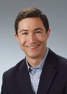 A man in a suit and tie smiling for the camera.