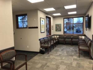 A waiting room with several chairs and windows.